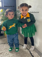 Toddler wearing green and gold hand-knitted rugby jersey with animal design, playing indoors