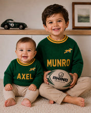 Two children wearing personalised green and gold hand-knitted rugby jerseys with animal design